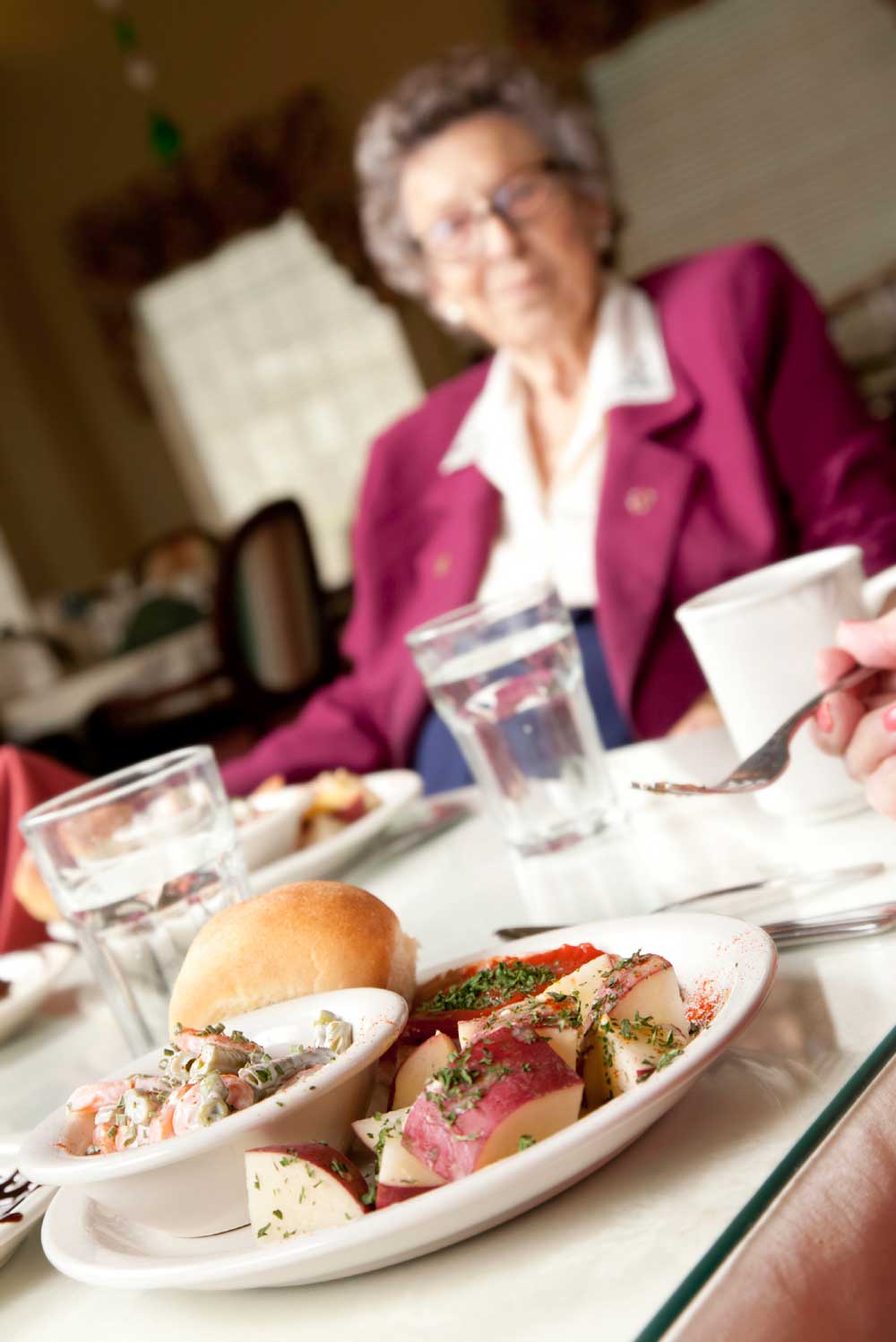 Older Woman Sitting at Table in Lunch Room